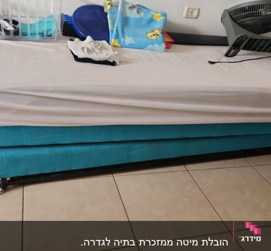 מיטה עם מצעים לבנים ומאוורר מונח עליה